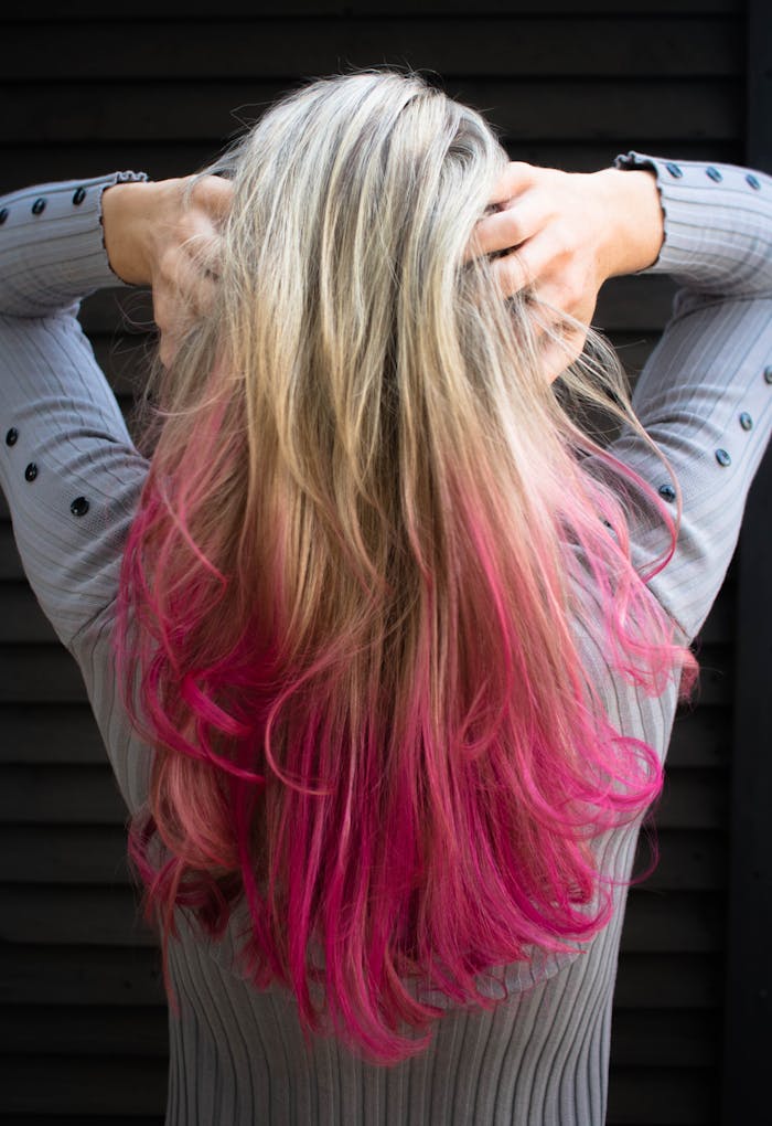 Close-up of a woman with blonde and pink ombre hair in a stylish pose.